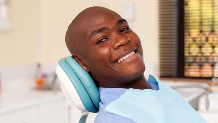 man in dentist exam chair smiling | dental care in tysons