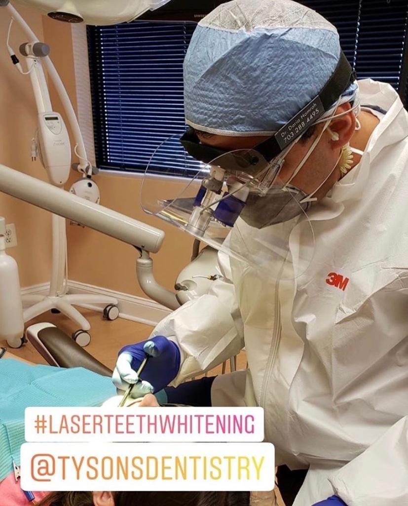 Dentist performing laser teeth whitening treatment 